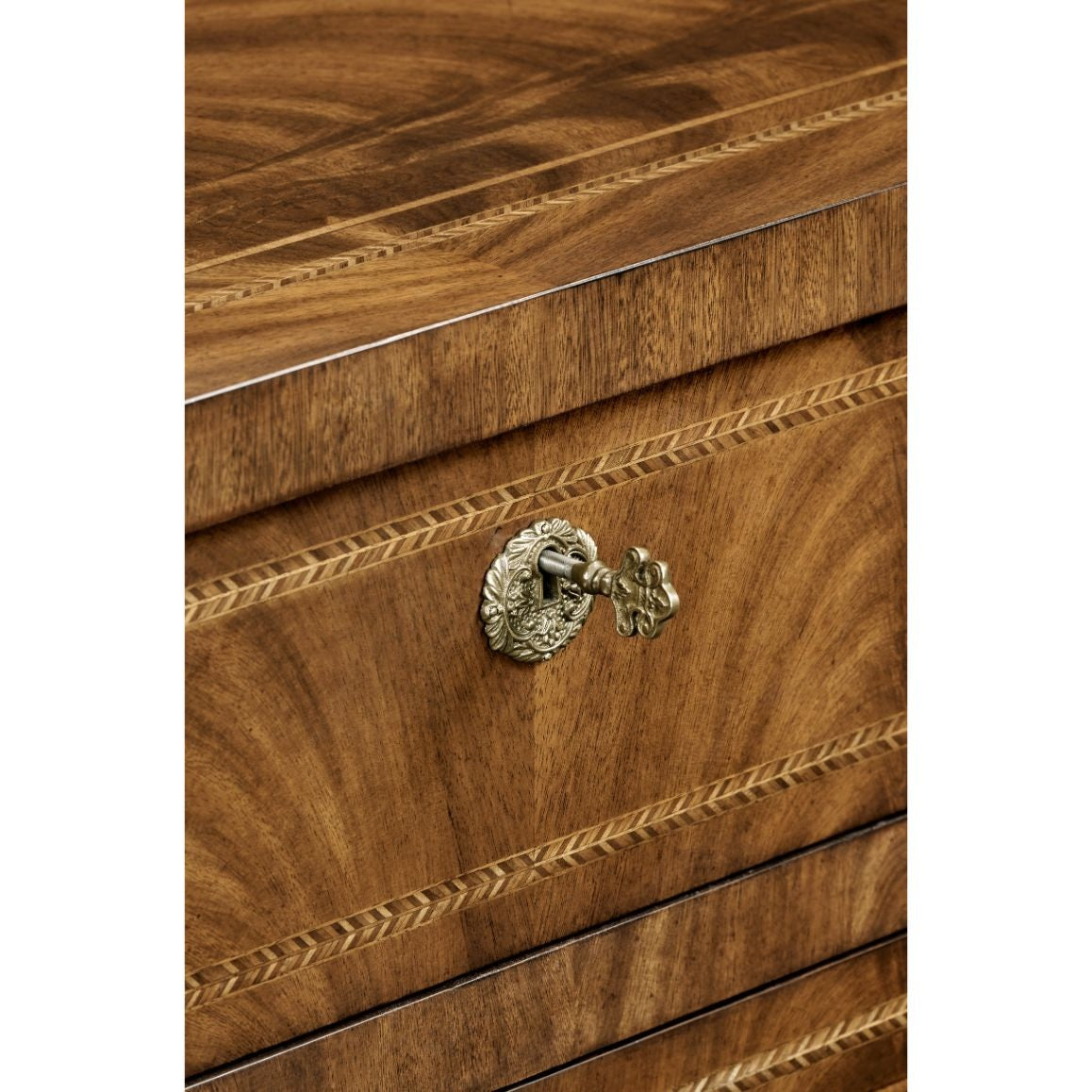 Detail shot of antique keyhole escutcheon with floral motifs on flamed walnut drawer front