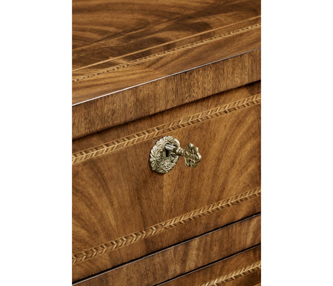 Detail shot of antique keyhole escutcheon with floral motifs on flamed walnut drawer front