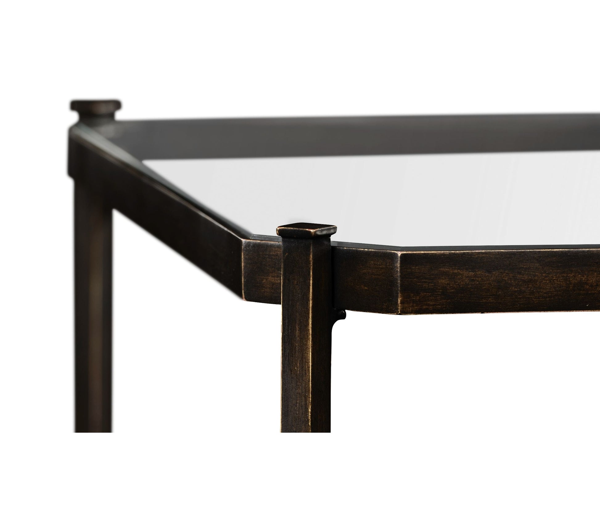 Close-up of bronze-finished metal corner joint on rectangular glass-top coffee table with flat-topped cap