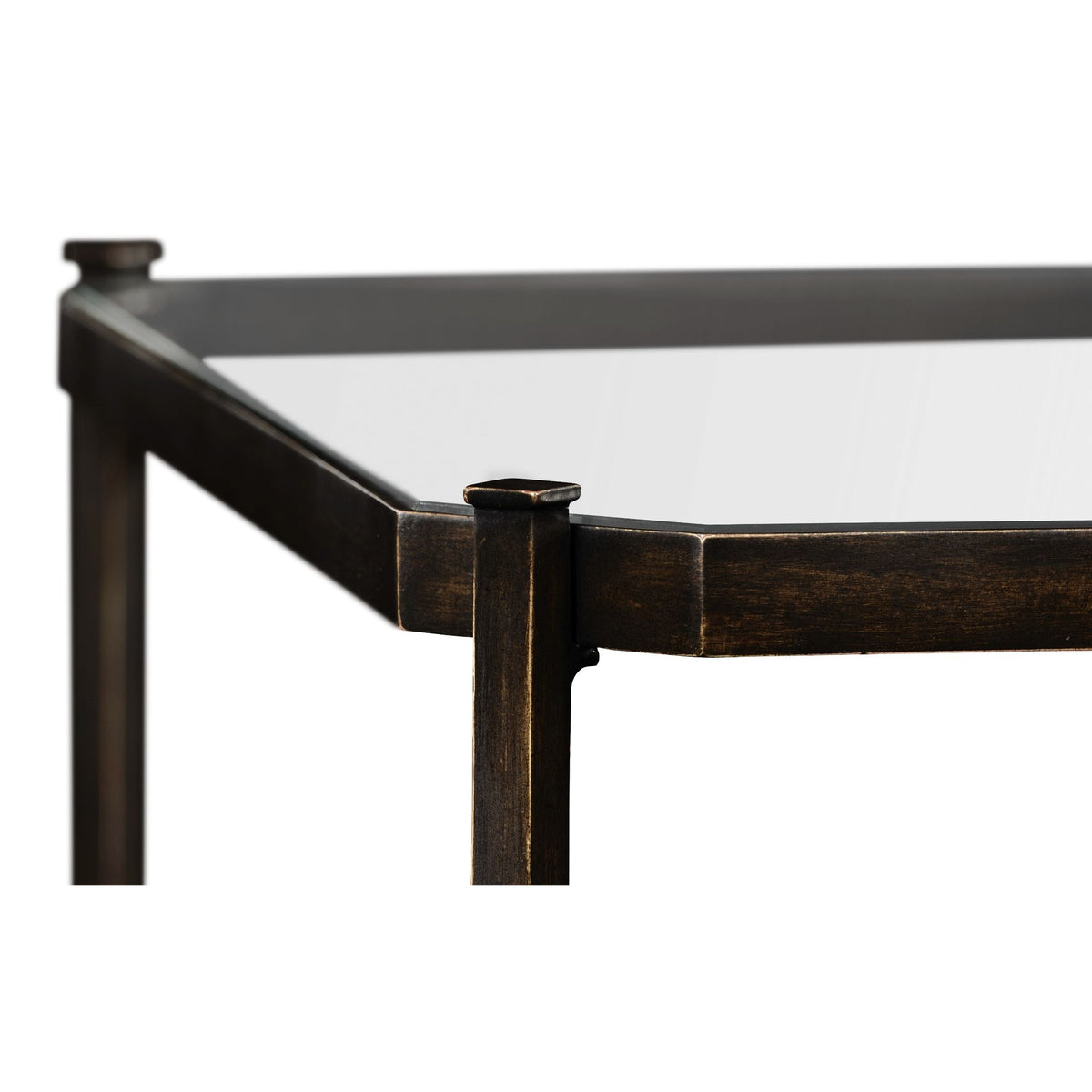Close-up of bronze-finished metal corner joint on rectangular glass-top coffee table with flat-topped cap