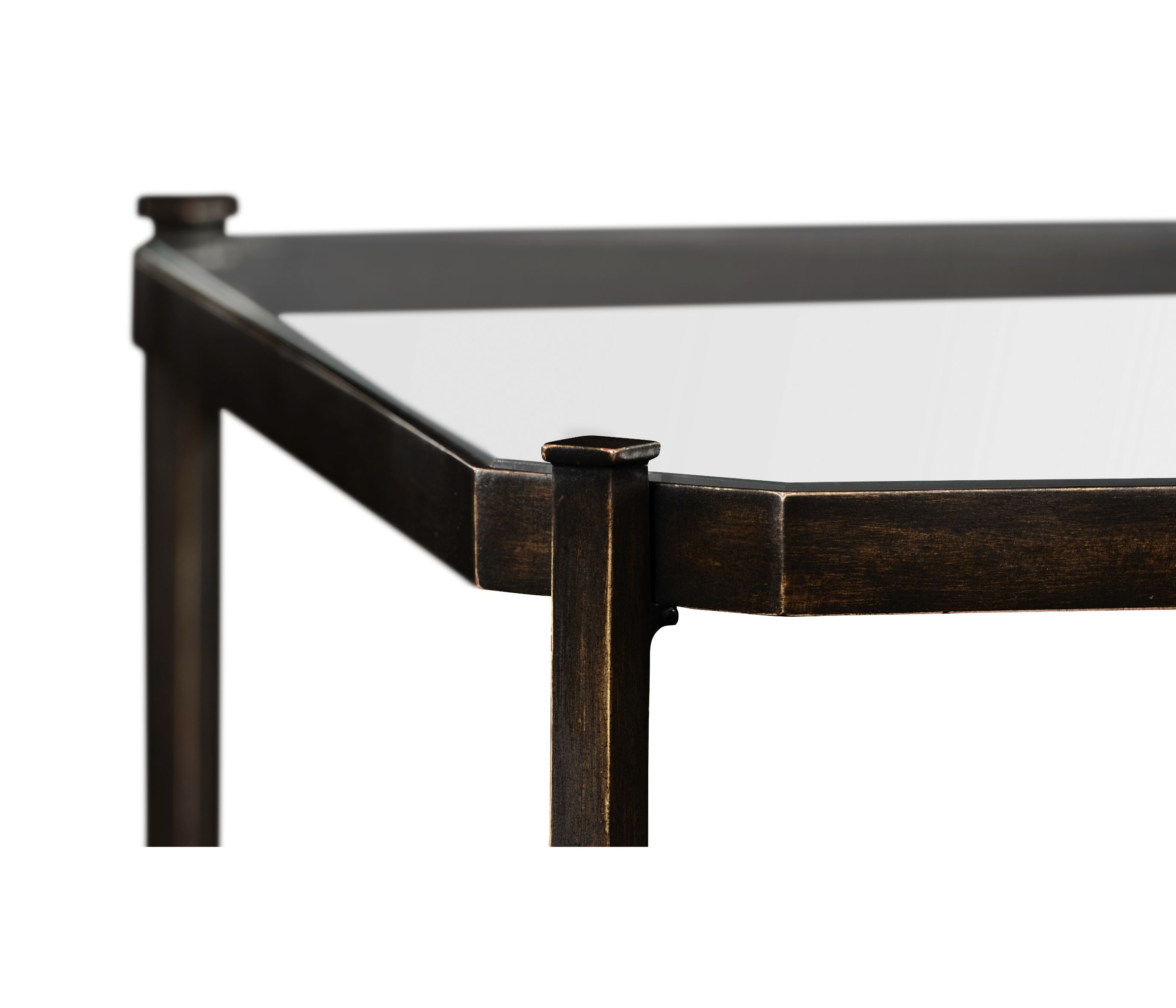 Close-up of bronze-finished metal corner joint on rectangular glass-top coffee table with flat-topped cap