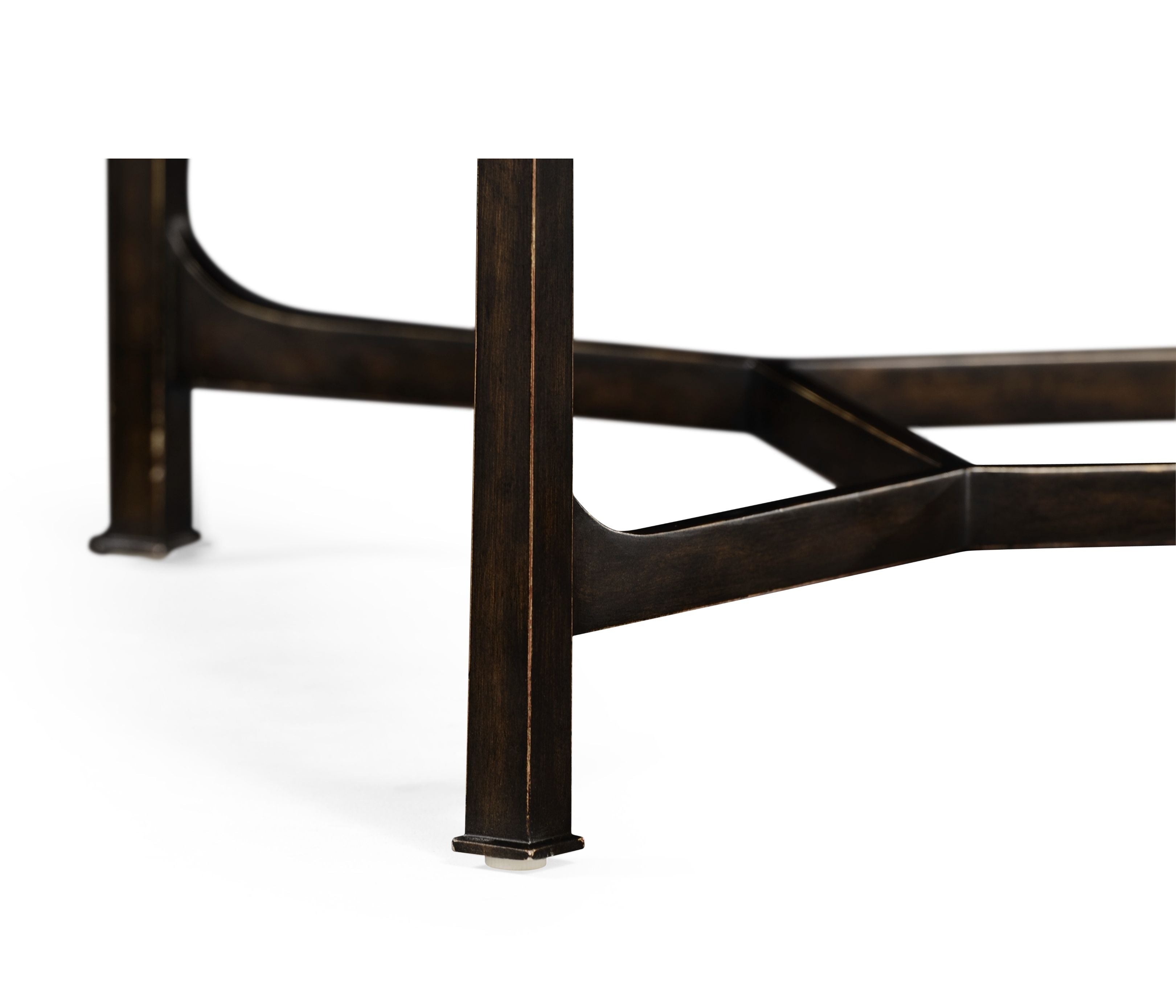 Low-angle detail of robust square bronze leg with beveled edge and X-shaped brace on modern coffee table