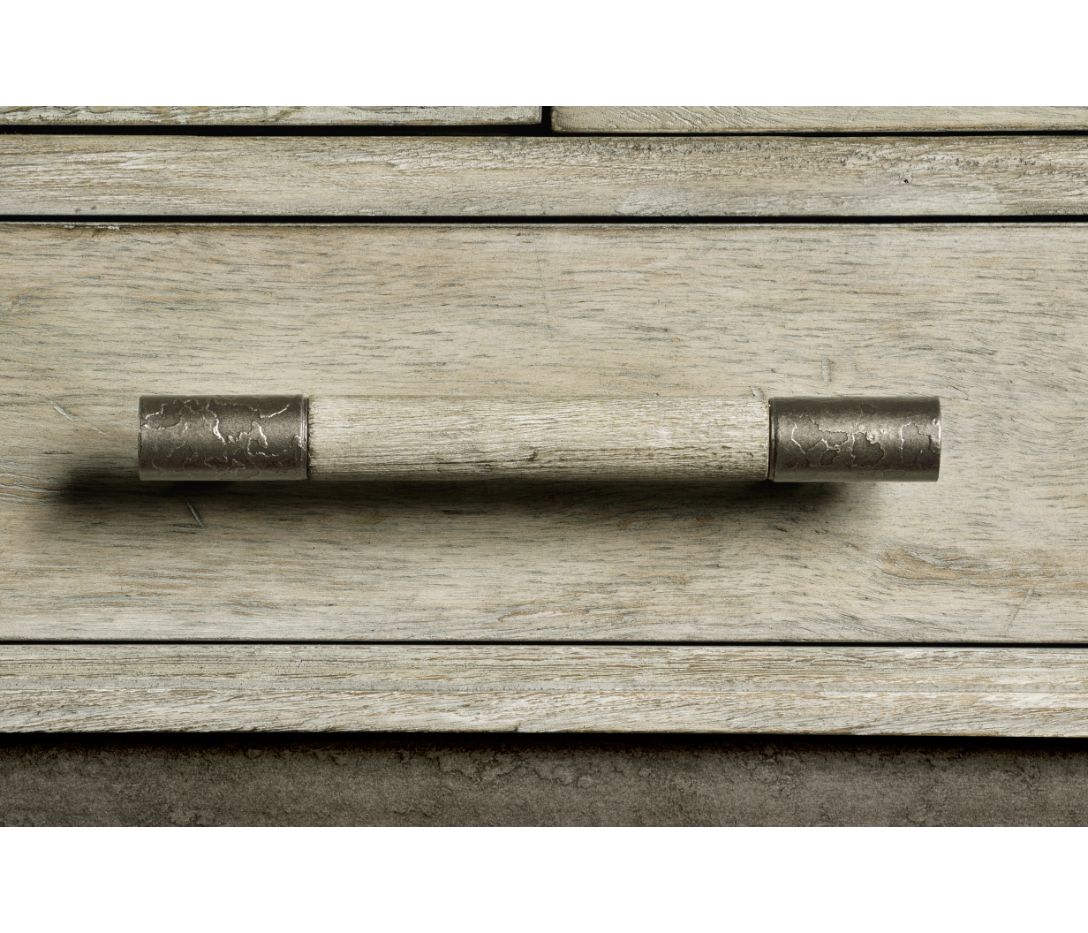 Close-up of distressed metallic and wood drawer handle on rustic grey parquetry cabinet