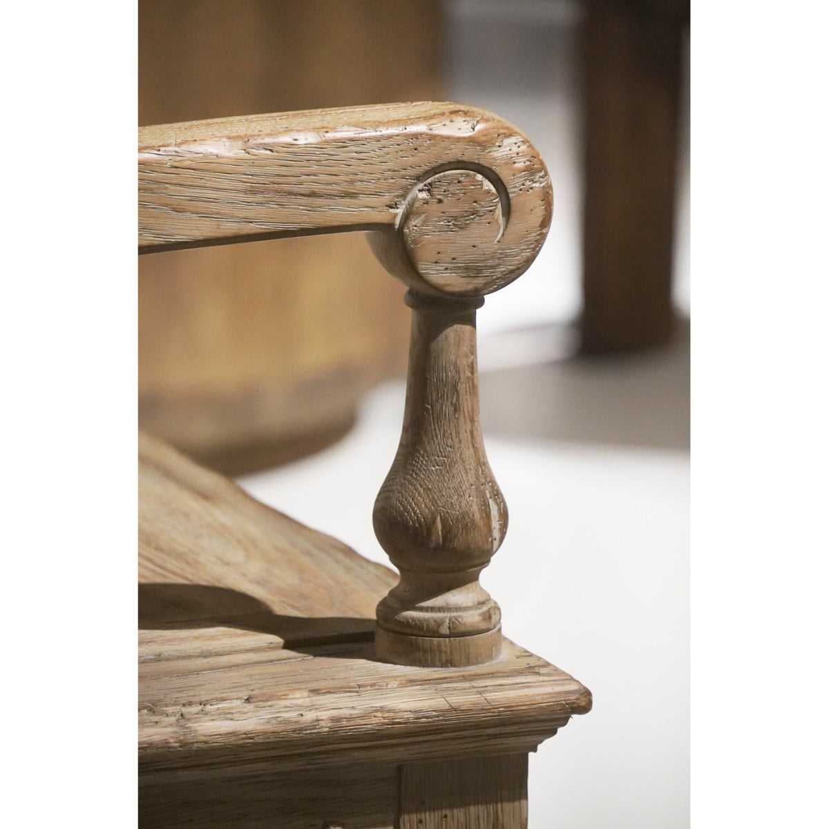 Detail of carved scrolled wooden armrest end cap on Jonathan Charles Sagehill bench