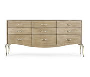 Front view of Jonathan Charles 9-drawer dresser featuring uniform silver ornamental handles and graceful curved silver legs