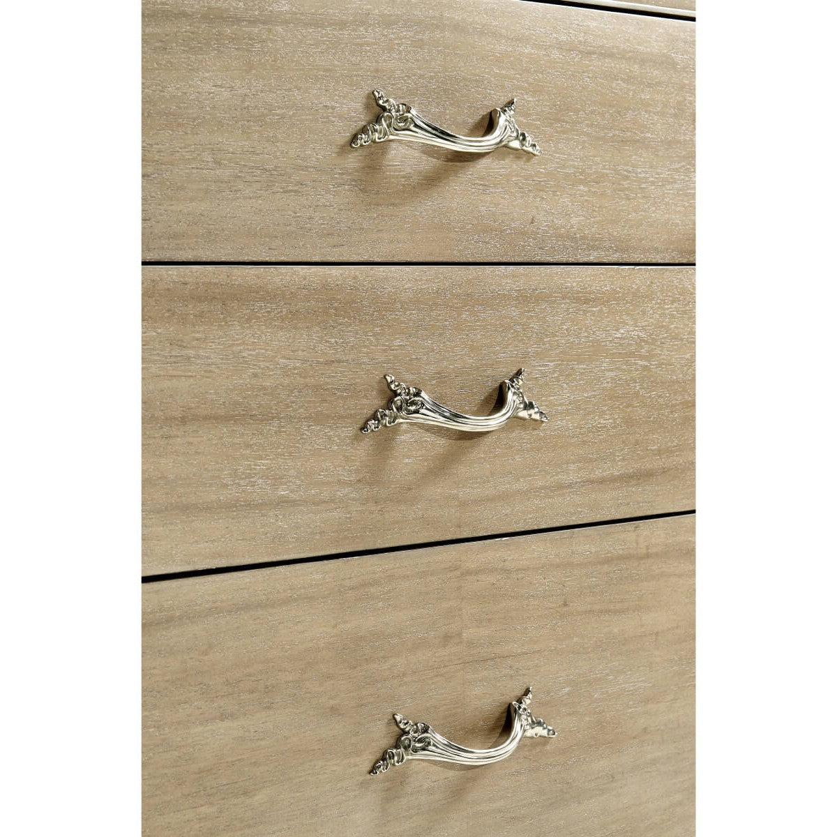 Detail shot of three drawers showing light brown wood grain texture and intricate silver scrollwork leaf handles