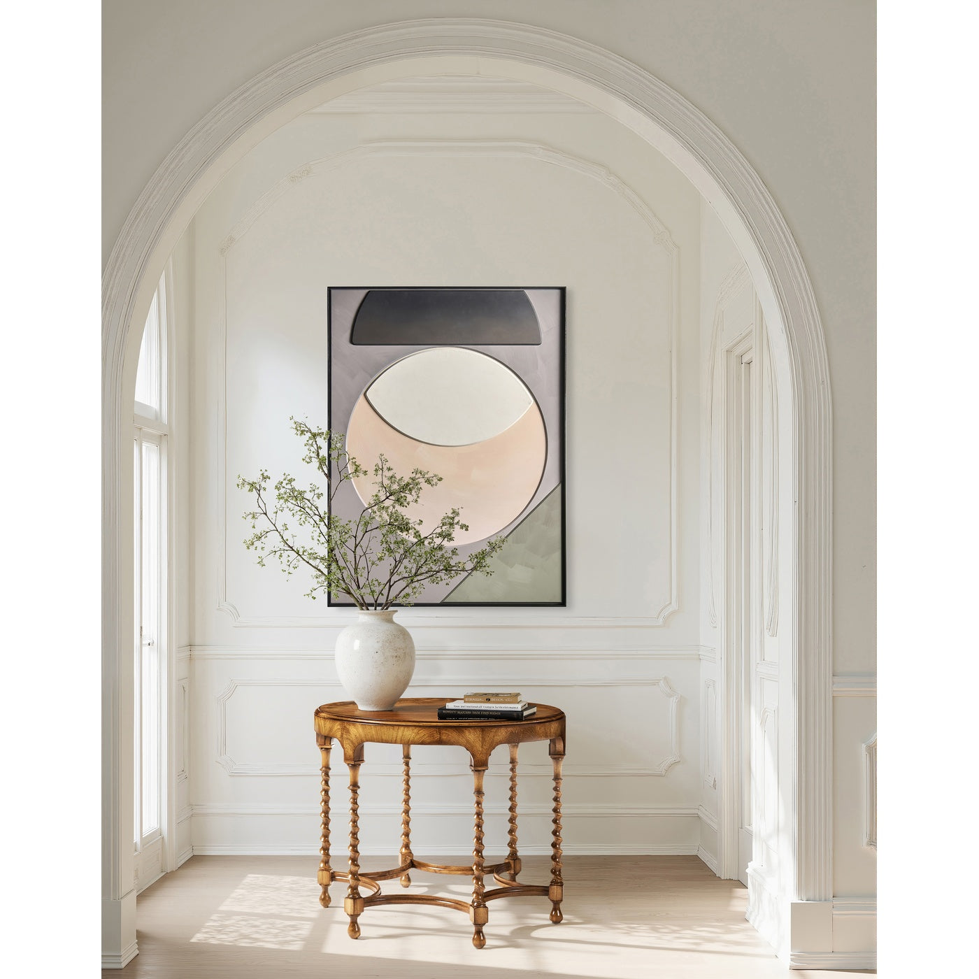 Round caramel walnut centre table under white archway holding ceramic vase and books
