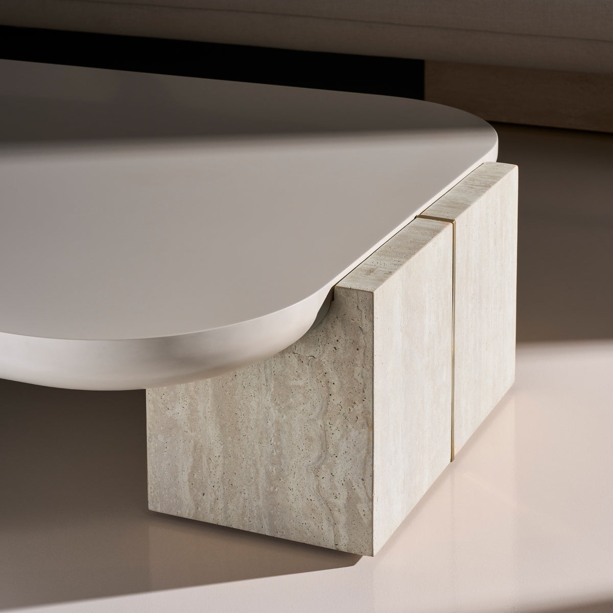Close-up of Caracole coffee table corner detail with rounded edge, Travertine texture, and brass seam inlay