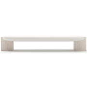 Side profile of Caracole low-slung coffee table showing curved Almond Milk top overhang on Travertine bases