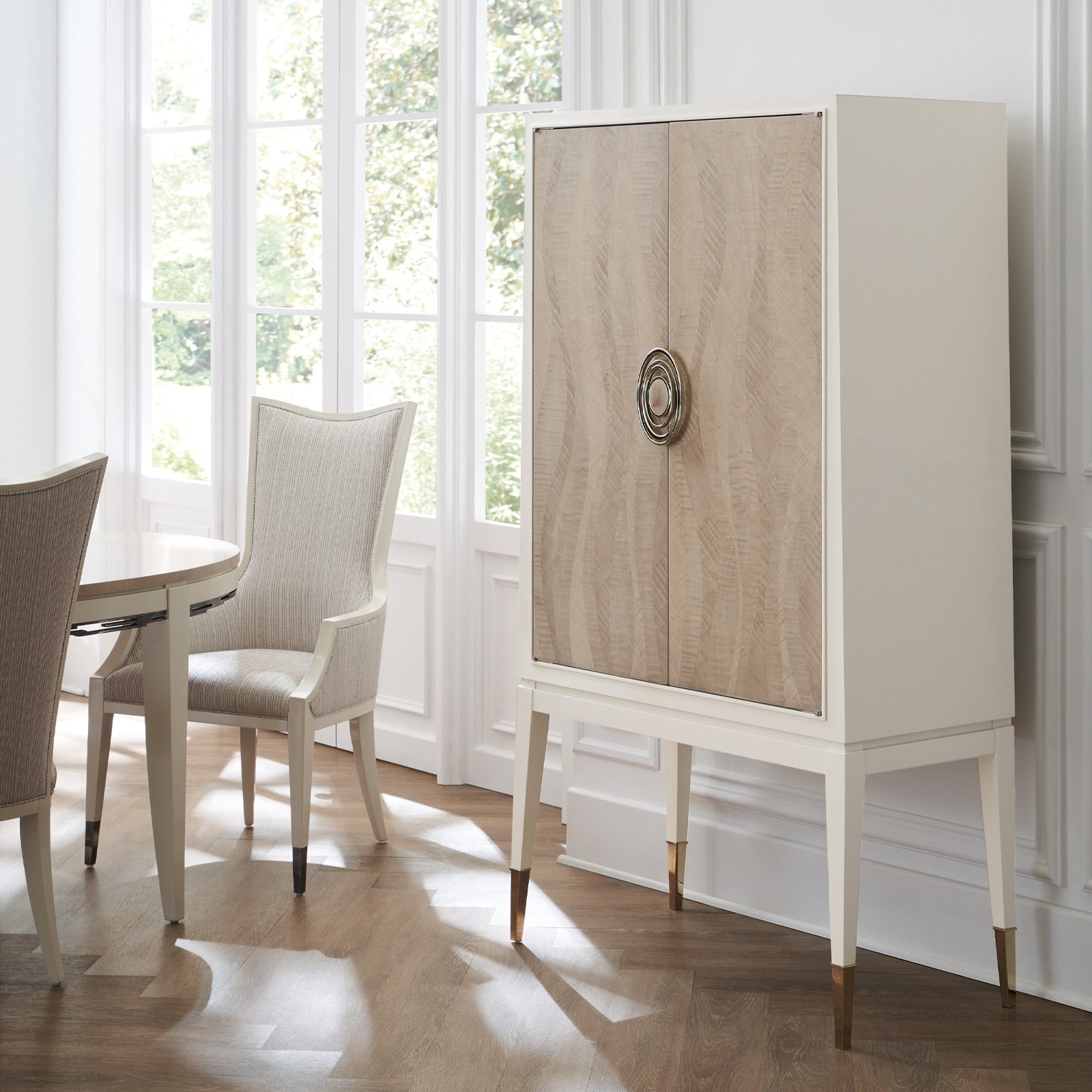Caracole Currents tall storage cabinet with grey curly maple doors in Chinchilla finish, Almond Milk case, gold ferrules, and rippling water texture