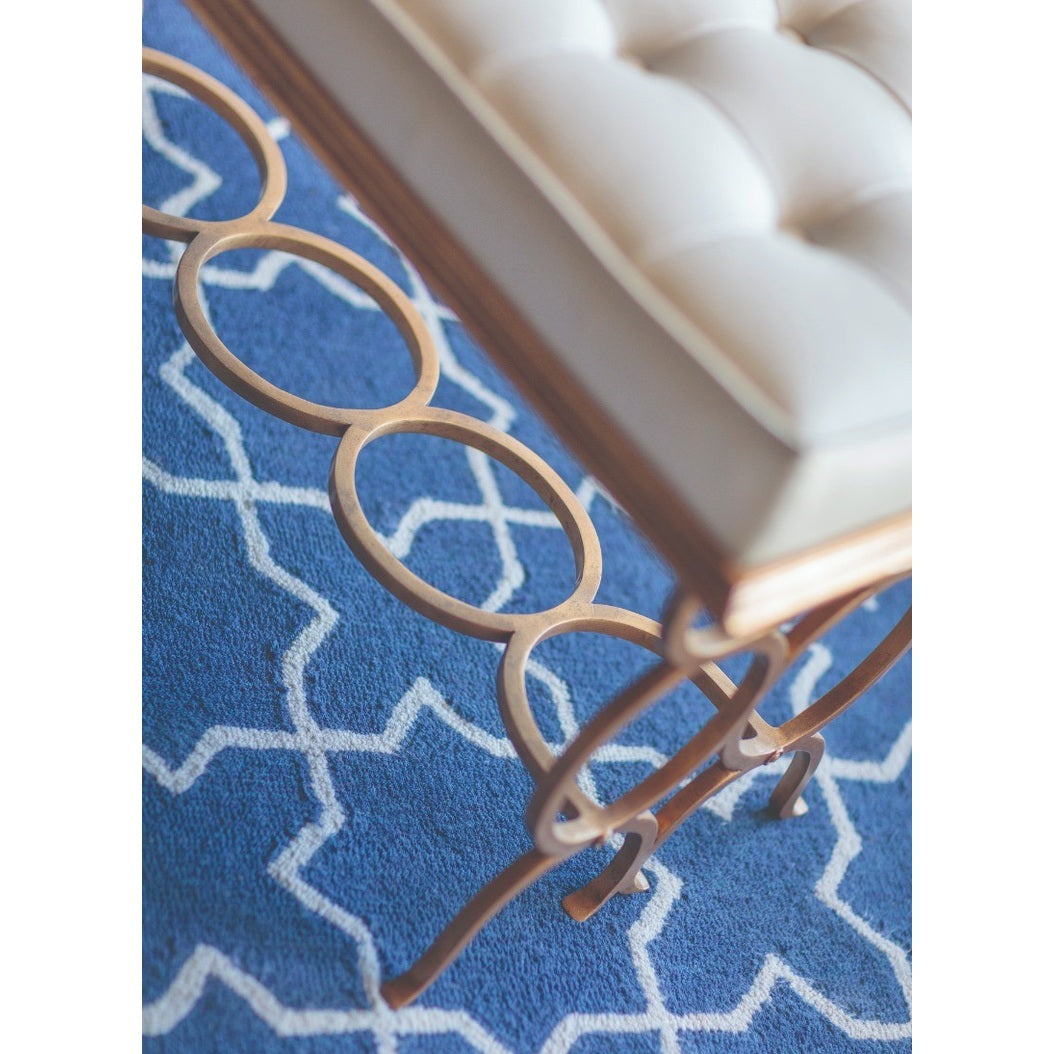 Close-up of Jonathan Charles Bench Circles showing gilded iron interlocking circle base on blue geometric rug