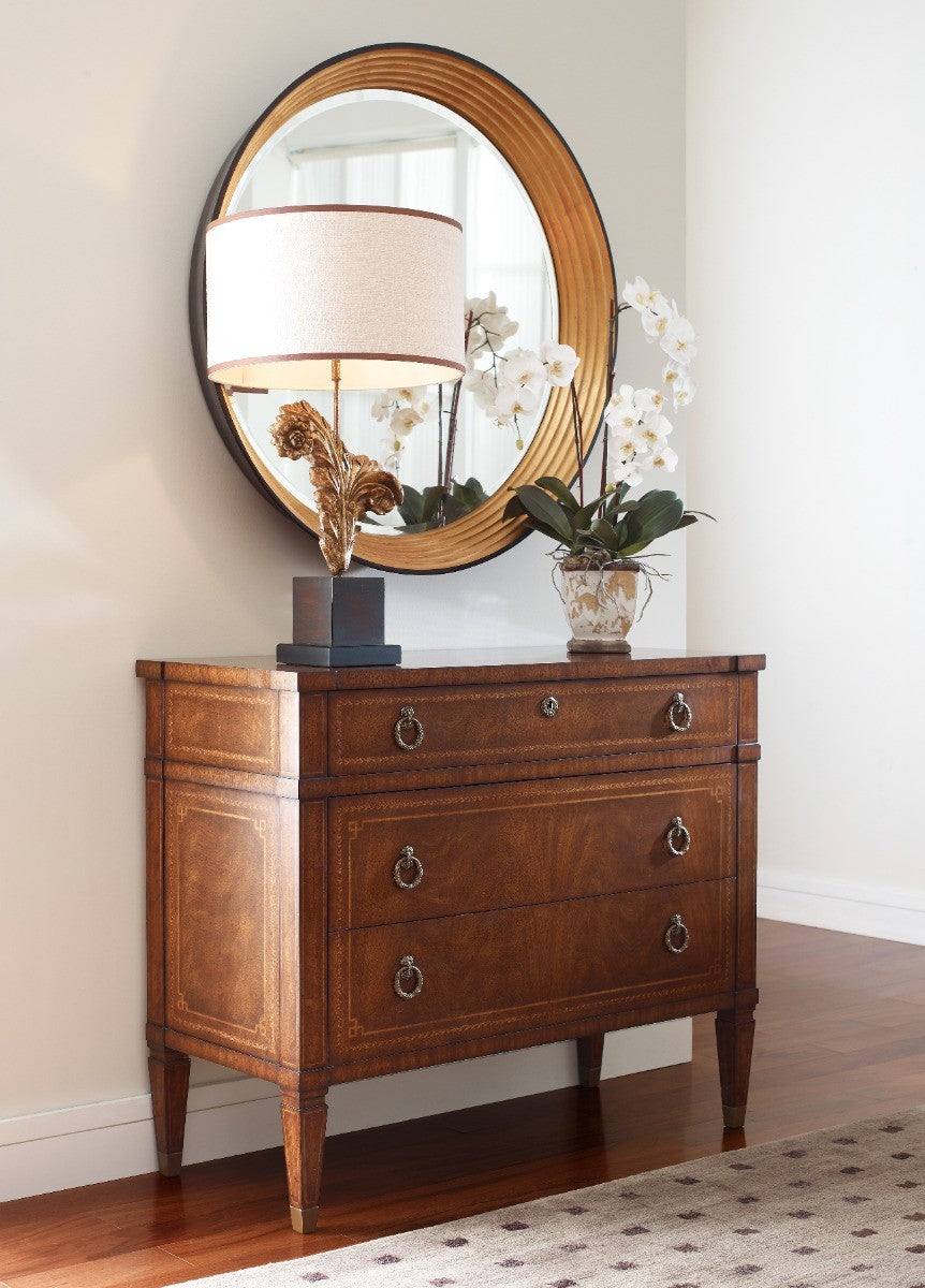 Walnut French Empire chest of three drawers with brass sabots and geometric inlay styled beside mirror