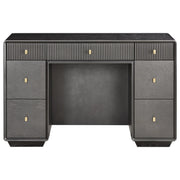 A dark gray wood writing desk with a ribbed top drawer section and three small round brass pulls, flanked by two larger drawers on each side with matching brass pulls, shown against a plain white background.