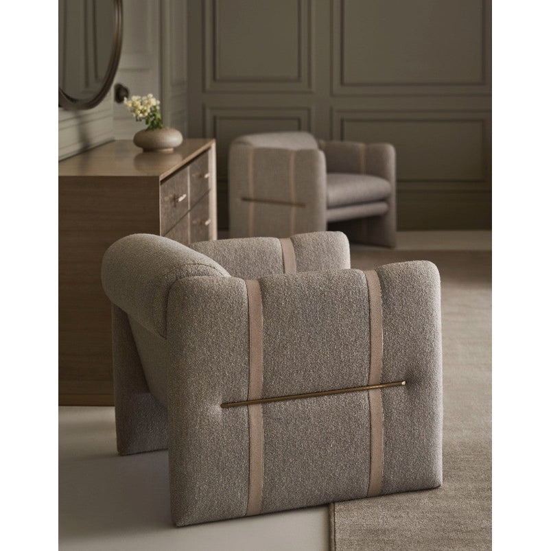 Light gray textured fabric armchair with brass bar detail positioned in front of Caracole Hang Up six-drawer dresser